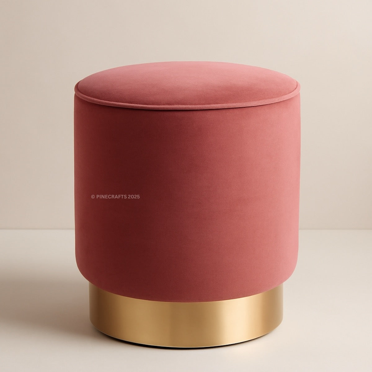 Pink velvet ottoman with gold base on a beige background