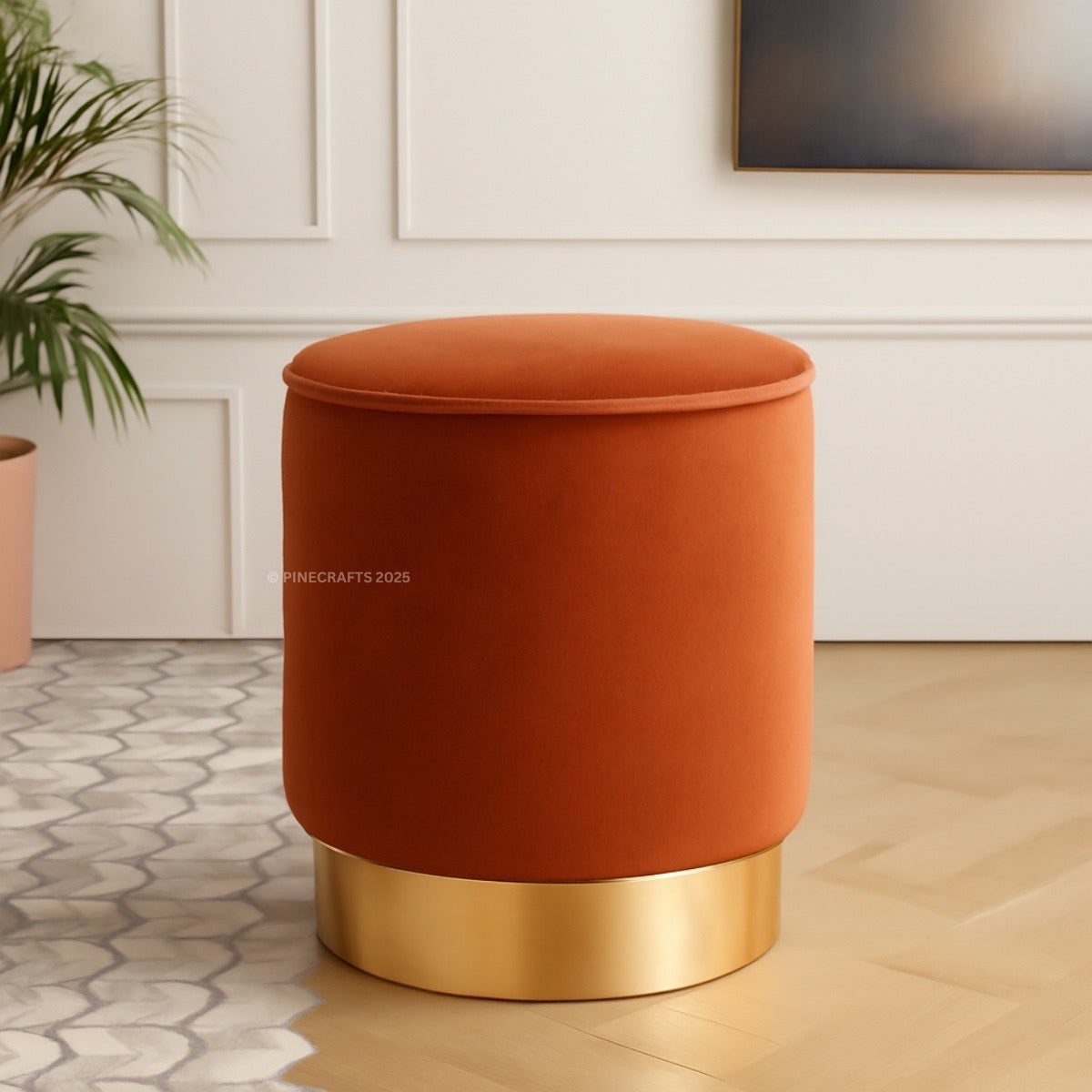 Orange ottoman with gold base in a room setting