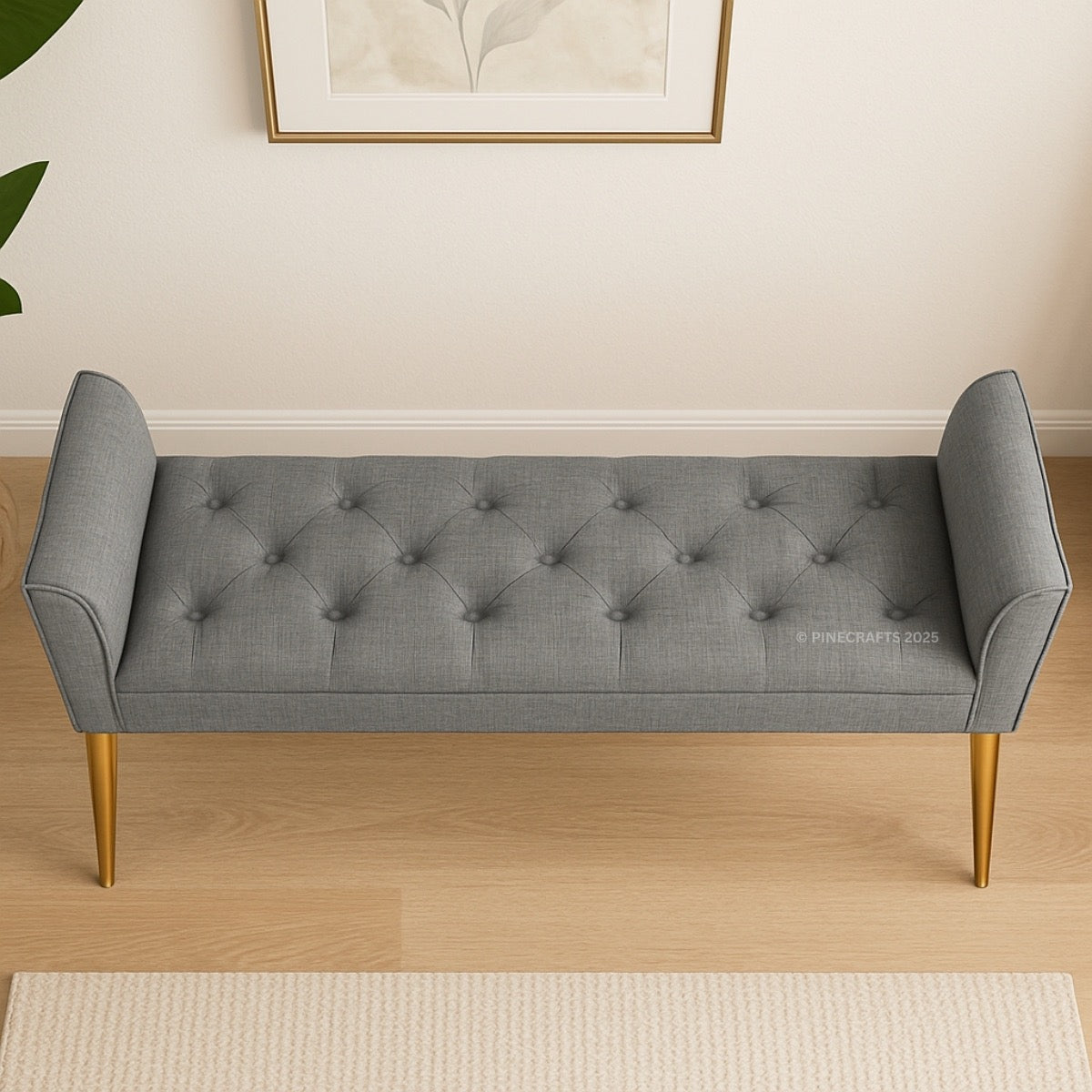 Gray tufted bench with gold legs on a wooden floor.