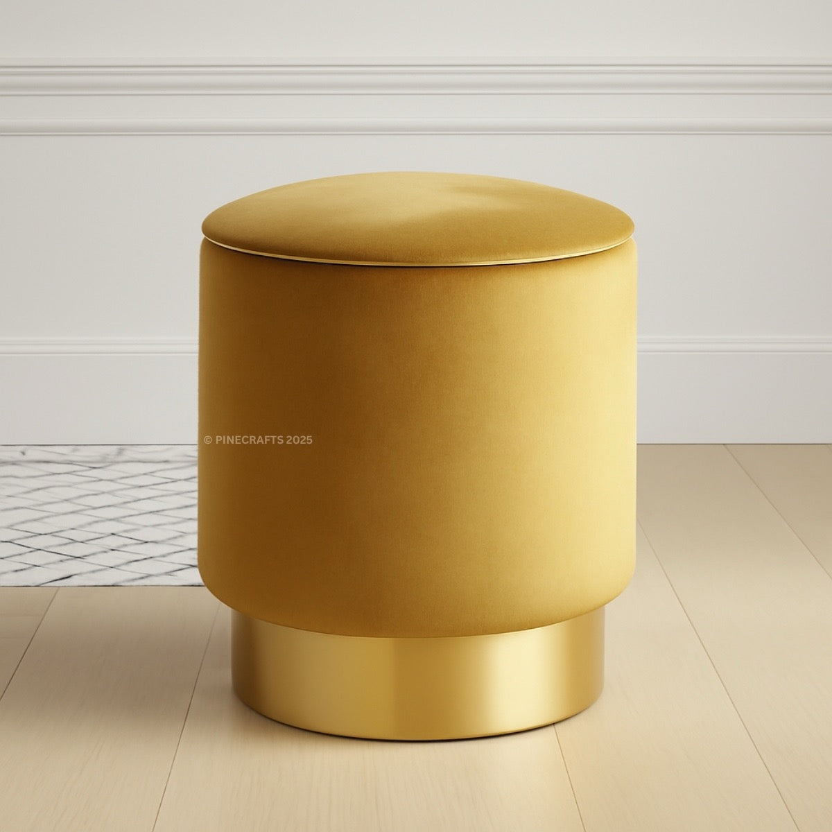 Gold cylindrical stool on a light wooden floor with a white paneled wall background.