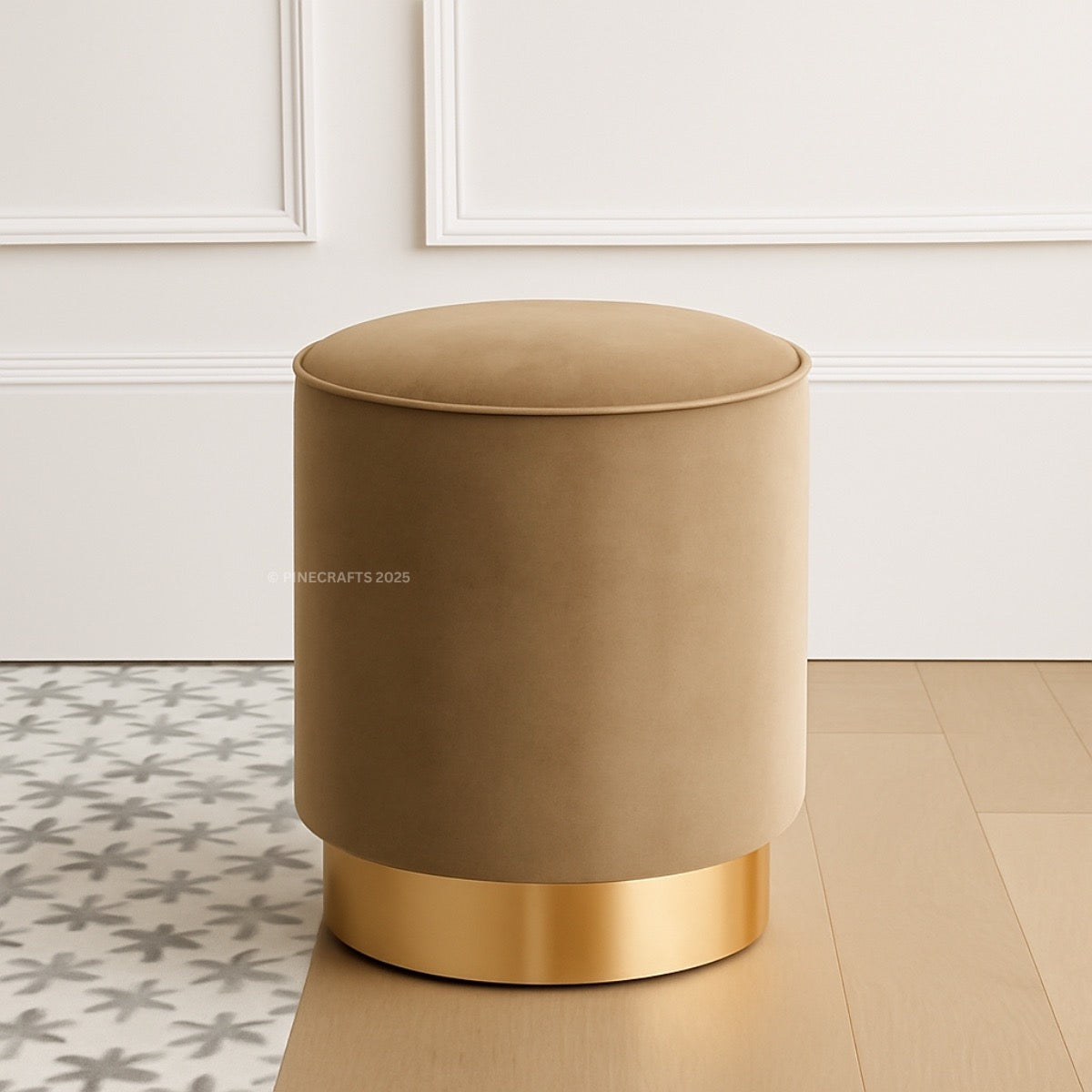 Beige round ottoman with gold base on a wooden floor.