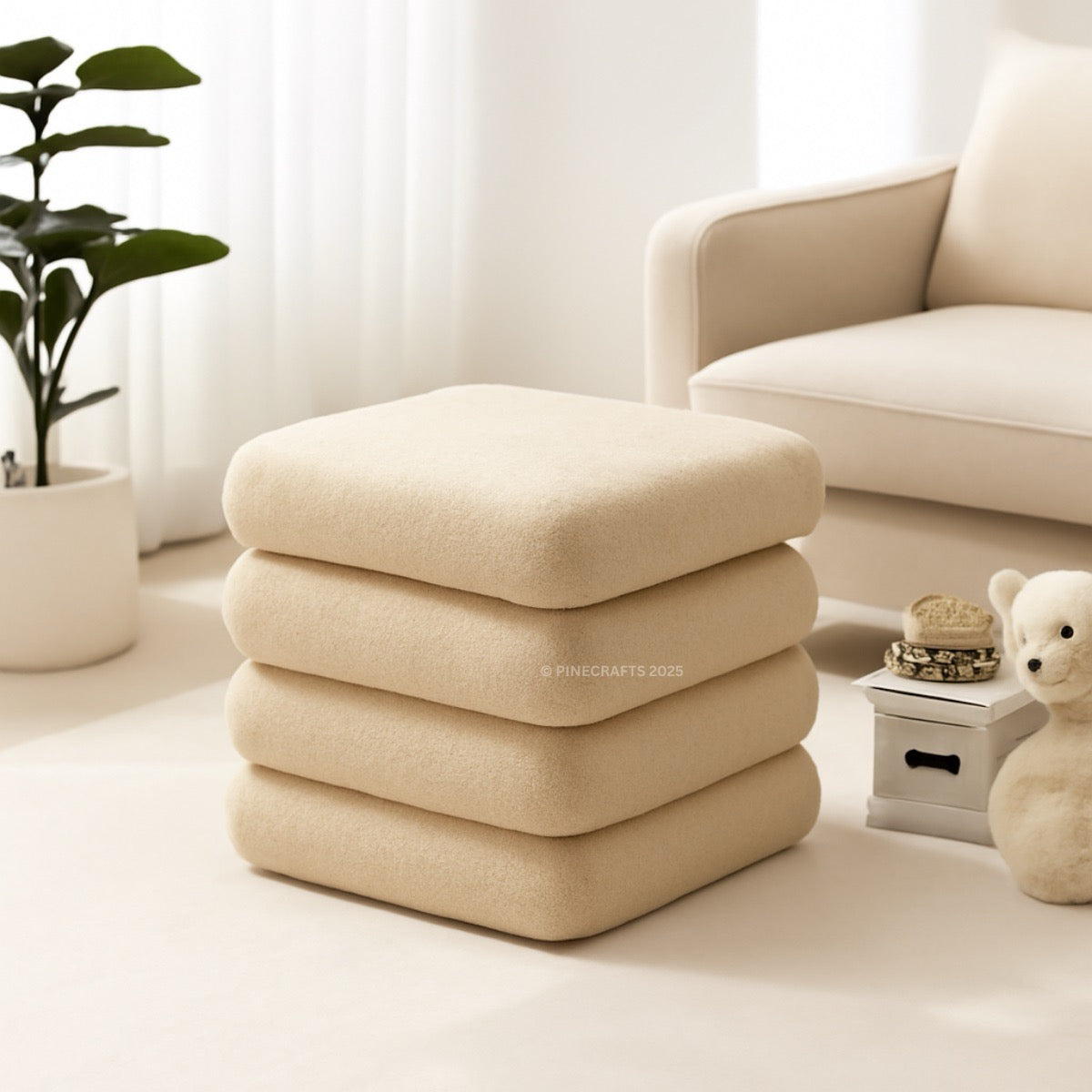 Stack of beige ottomans in a living room setting with a plant and teddy bear.