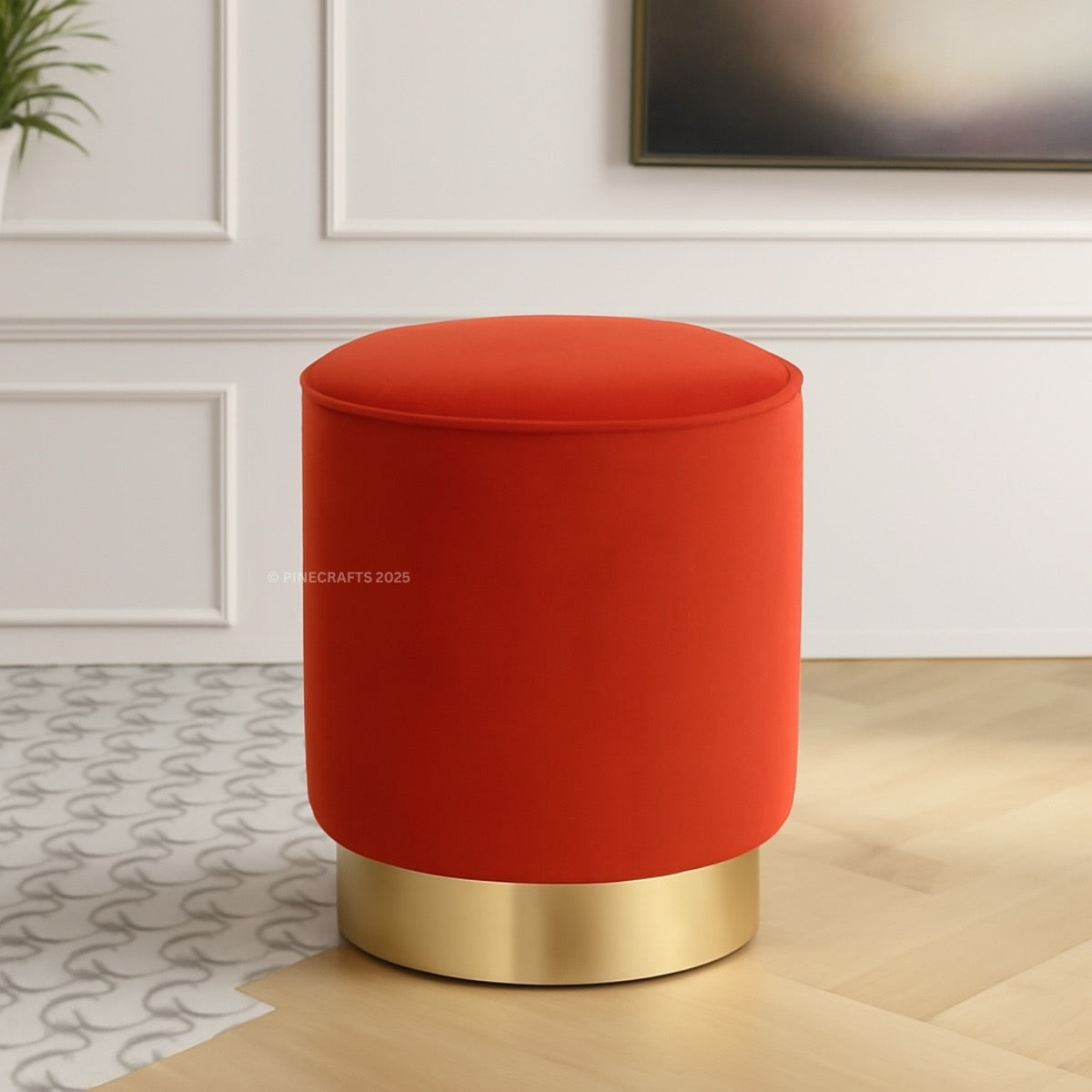 Red cushioned stool with gold base on a wooden floor.