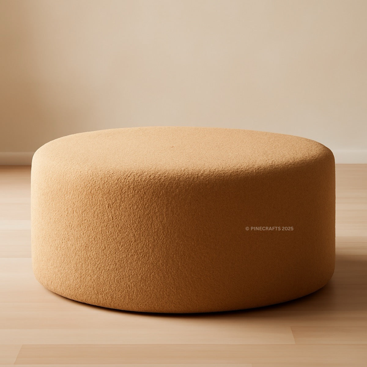Round beige ottoman on a wooden floor with a neutral background