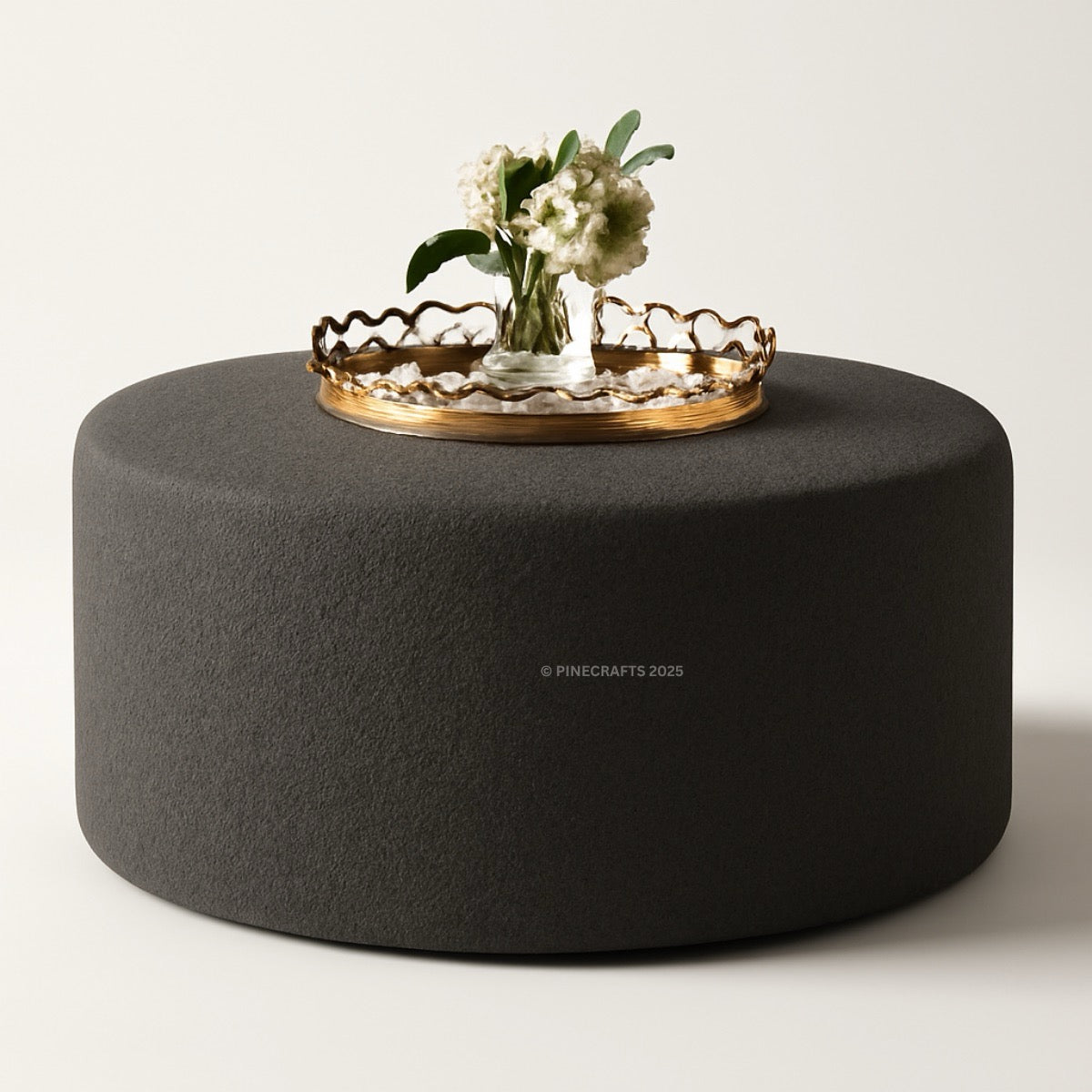 Round dark gray ottoman with a gold tray and flowers on a light background