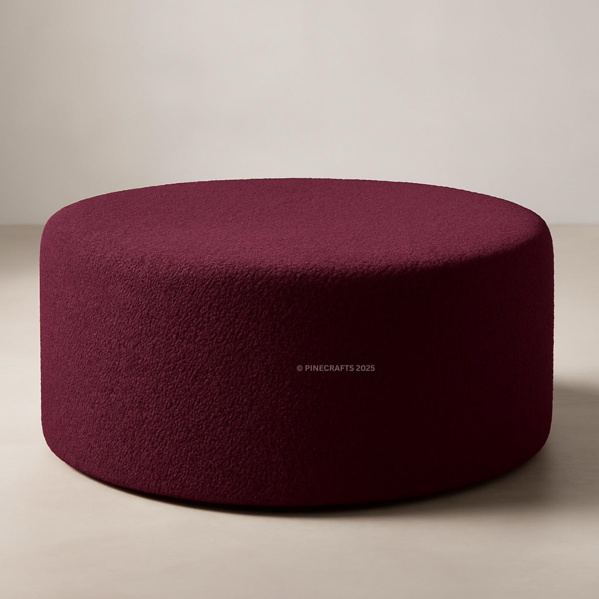 Round, burgundy ottoman on a neutral background