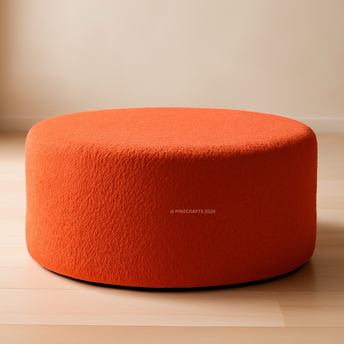 Orange ottoman on a wooden floor with a beige wall background