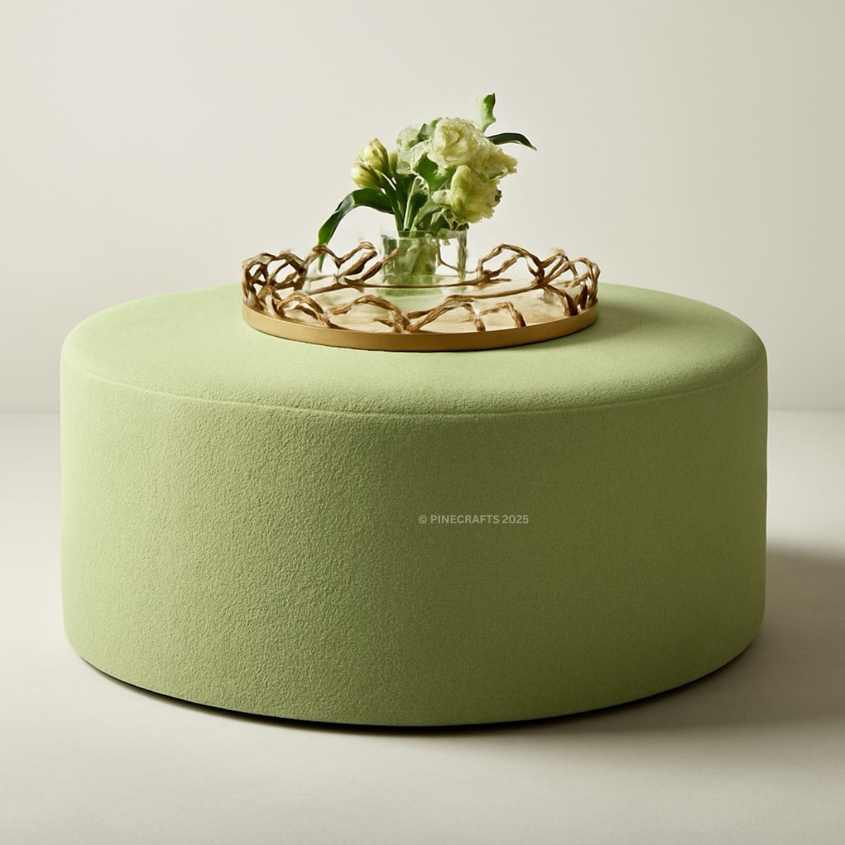Green ottoman with a decorative tray and flowers on a light background