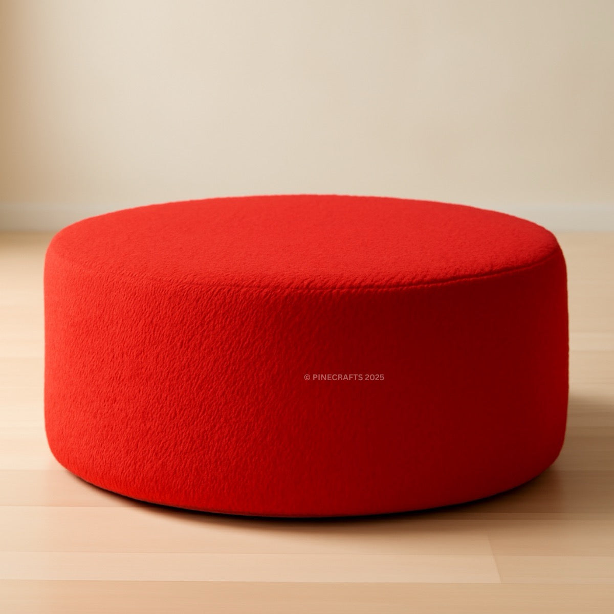Red ottoman on a wooden floor with a plain background