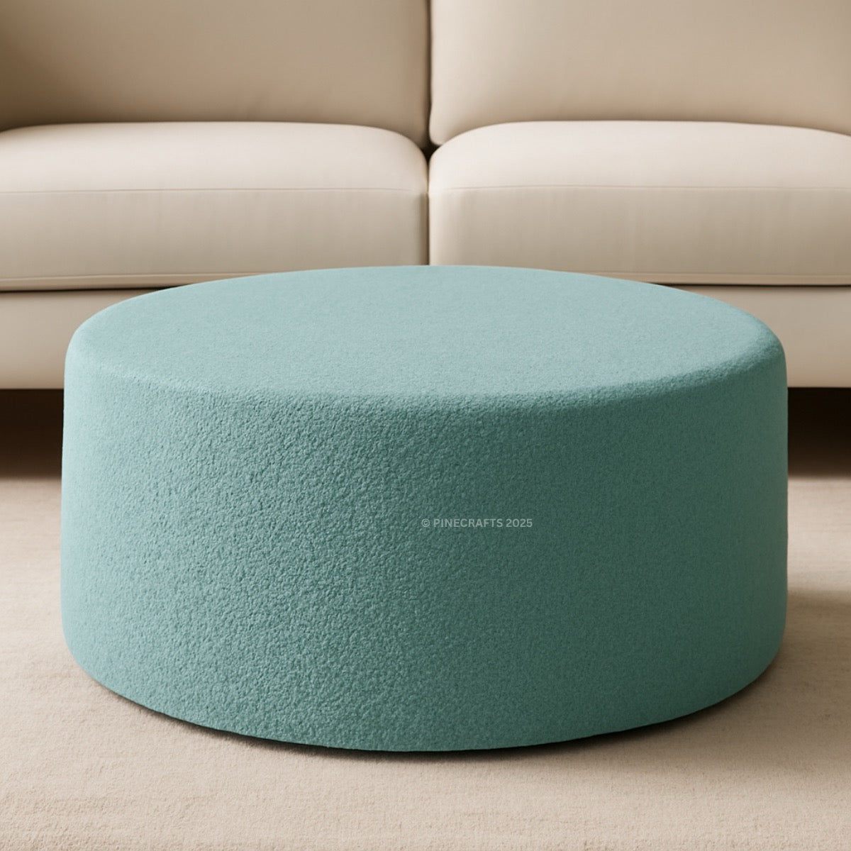 Round teal ottoman in front of a beige sofa