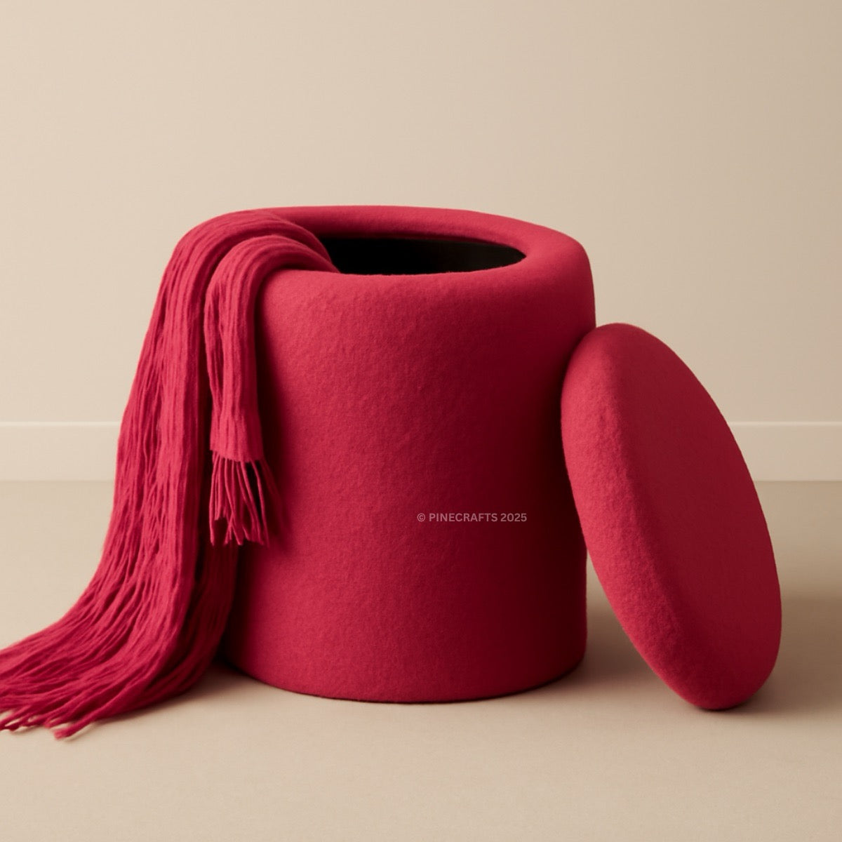 Red fabric ottoman with a matching blanket draped over it on a beige background