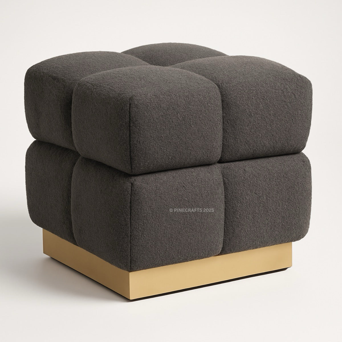 Gray upholstered cube with gold base on a white background