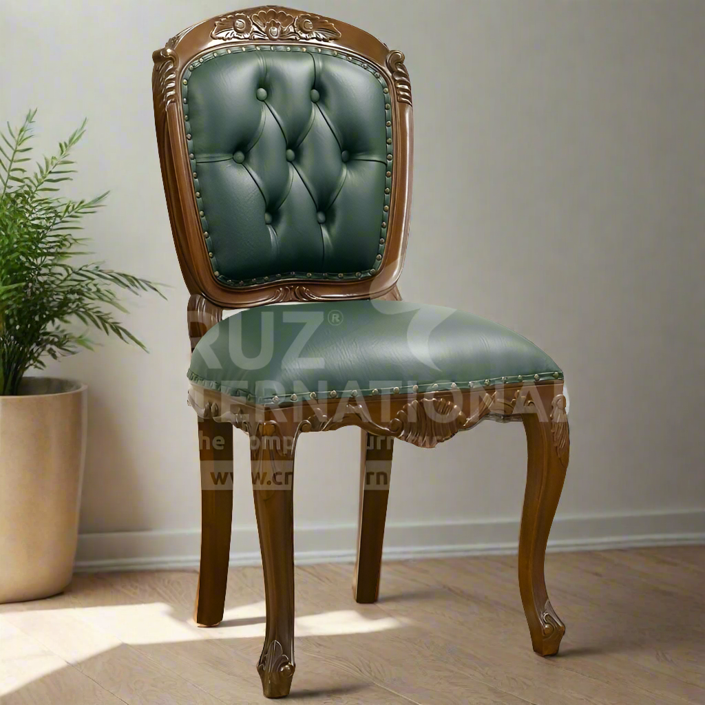 A classic Emilia dining chair with a carved wooden frame and green upholstery, standing in a room with a potted plant and wood flooring.