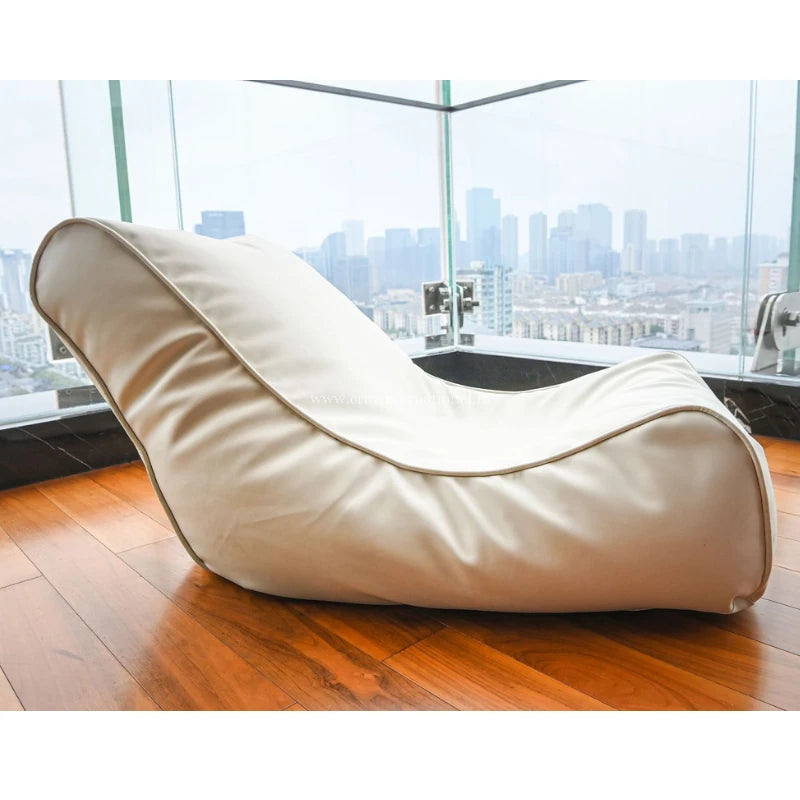 A modern white yoga chair with a high backrest and cushioned padding, placed on a wooden floor with a window in the background showing a cityscape.
