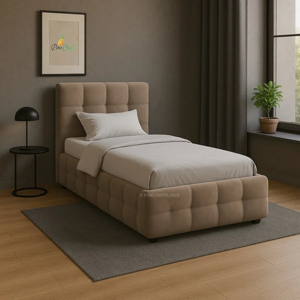 Beige upholstered bed in a room with a lamp, plant, and framed picture on the wall.