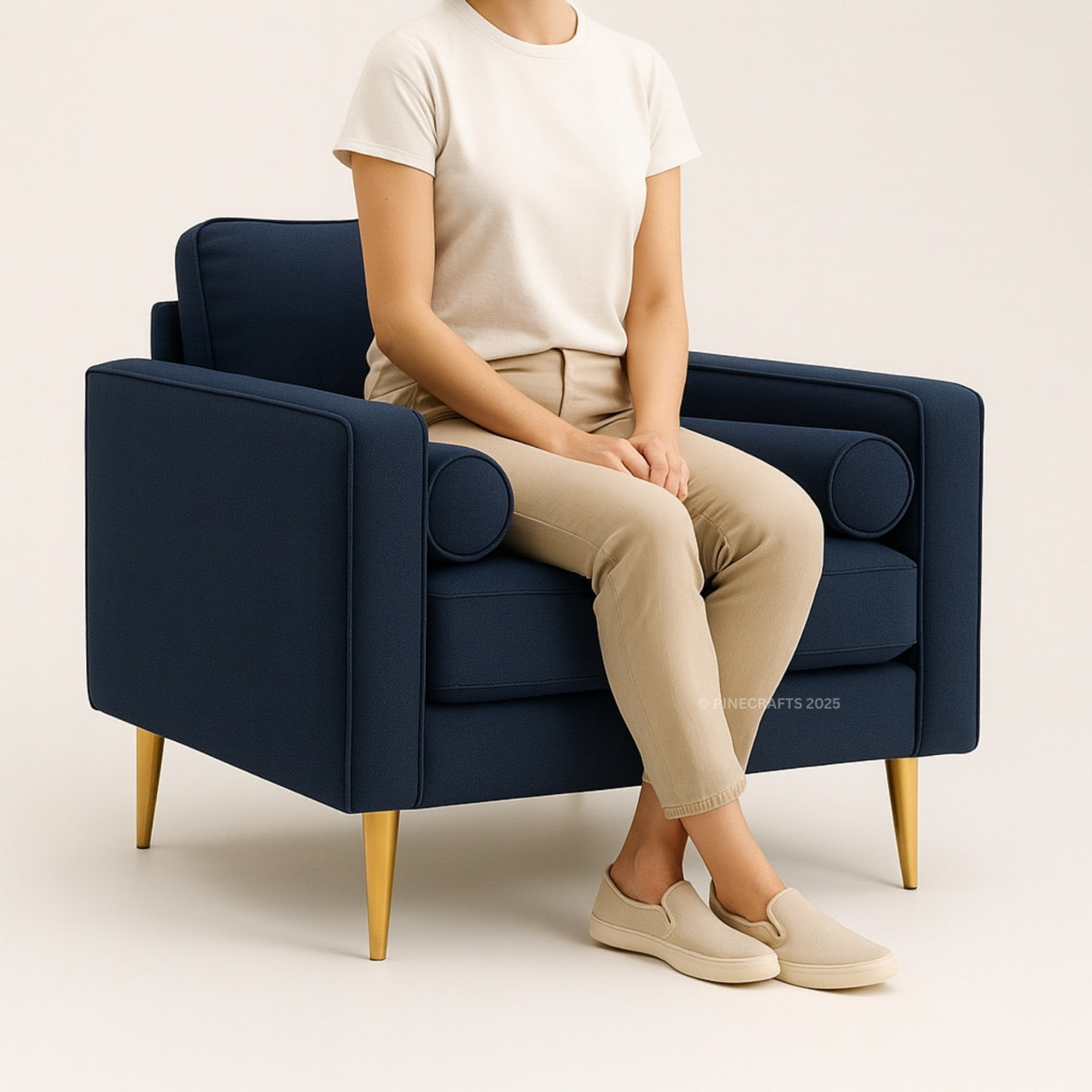 Person sitting on a navy blue armchair with gold legs against a beige background