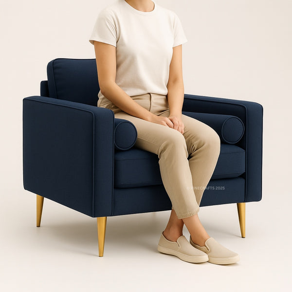 Person sitting on a navy blue armchair with gold legs against a beige background