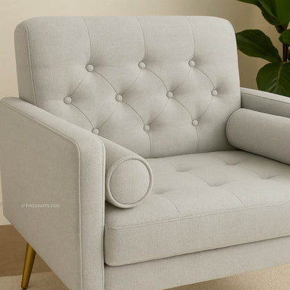 Gray tufted armchair with gold legs on a neutral background