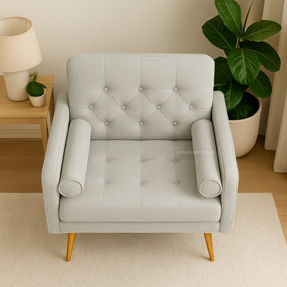 Gray tufted armchair in a room with a side table and plants.