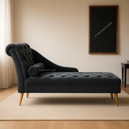 Black tufted chaise lounge in a room with a beige wall and wooden floor.