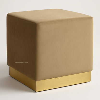 Beige cube-shaped ottoman with a gold base on a white background