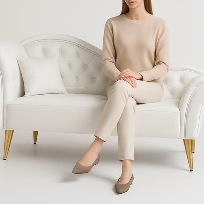Woman sitting on a white armchair wearing a beige outfit.