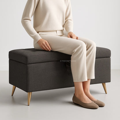 Person sitting on a dark gray storage bench with a plain background