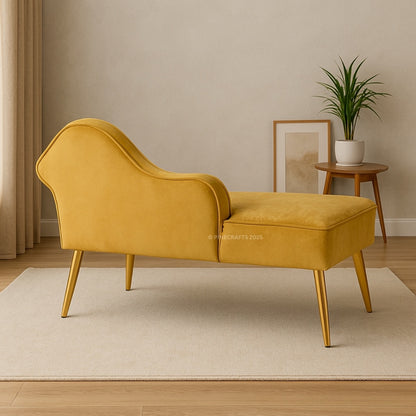 Yellow chaise lounge in a room with a plant and framed picture on a table.