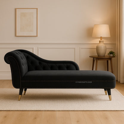 Black chaise lounge in a living room setting with a lamp and framed picture on the wall.