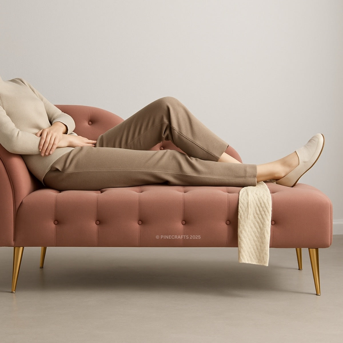 Person lounging on a pink tufted bench with gold legs against a neutral background