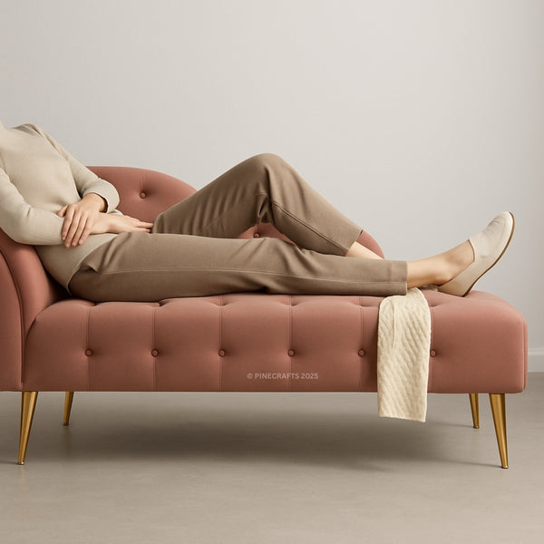 Person lounging on a pink tufted bench with gold legs against a neutral background