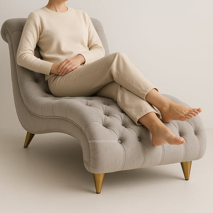 Person sitting on a gray tufted chair with a neutral background