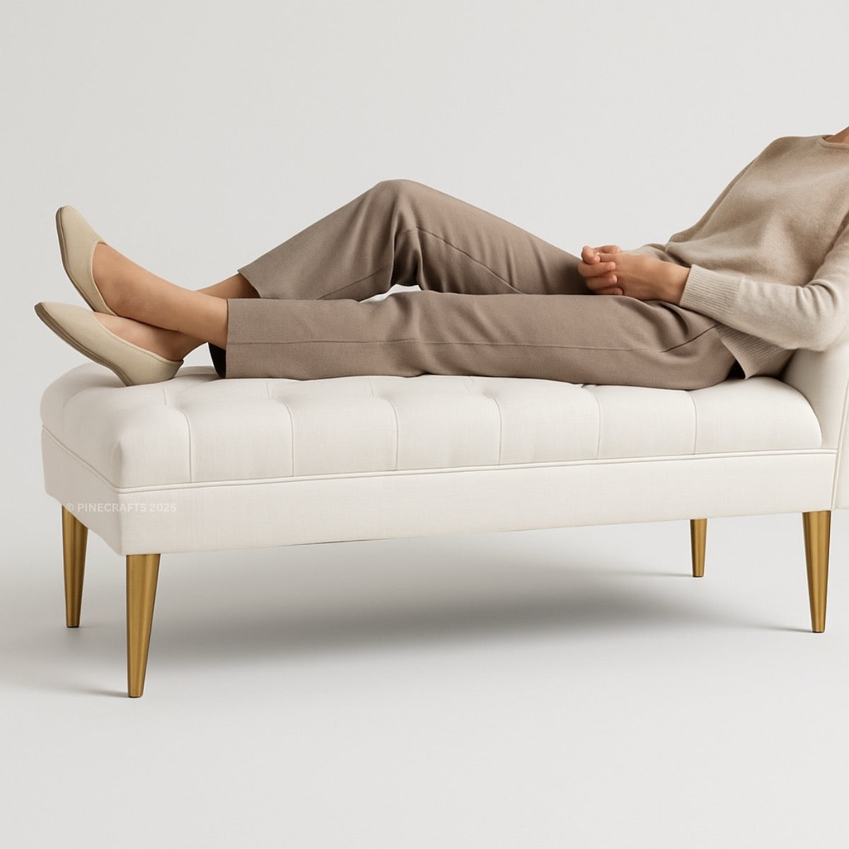 Person sitting on a white bench wearing beige pants and shoes against a light gray background