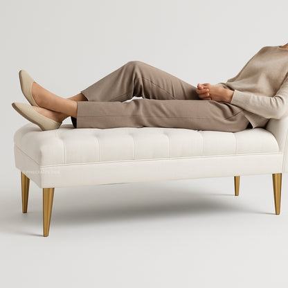 Person sitting on a white bench wearing beige pants and shoes against a light gray background