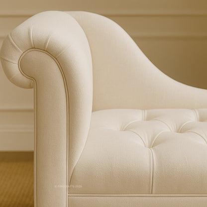 Beige tufted sofa with curved armrests against a beige wall.