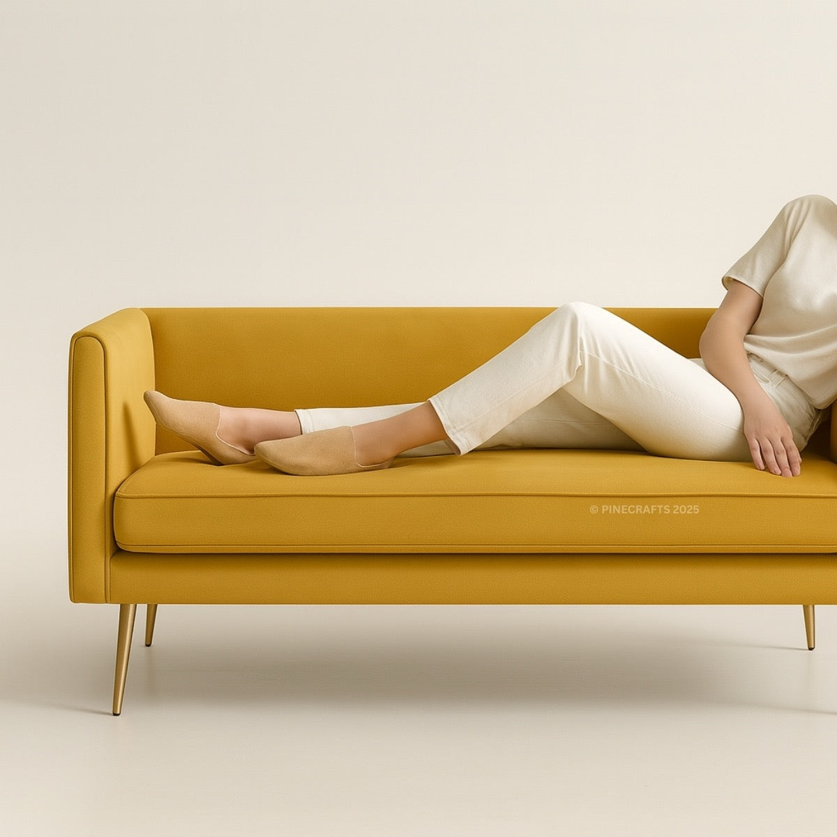 Person sitting on a mustard yellow sofa against a beige background