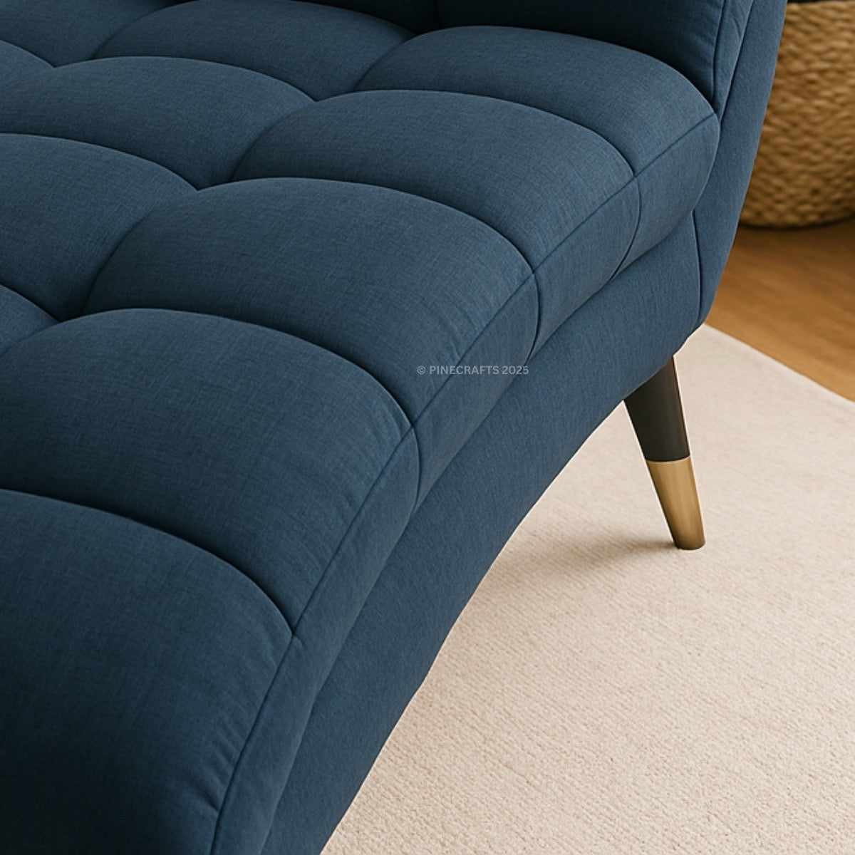 Close-up of a blue tufted sofa with gold legs on a beige carpet.