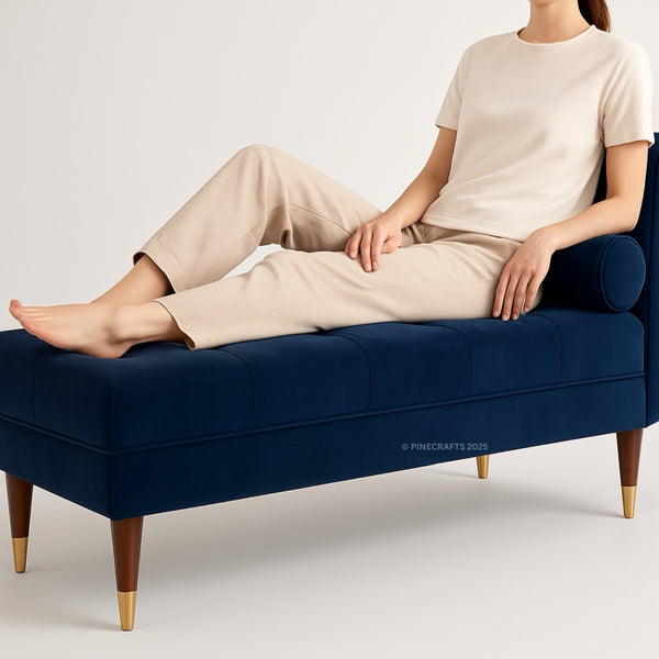 Person sitting on a navy blue bench with gold legs against a plain background