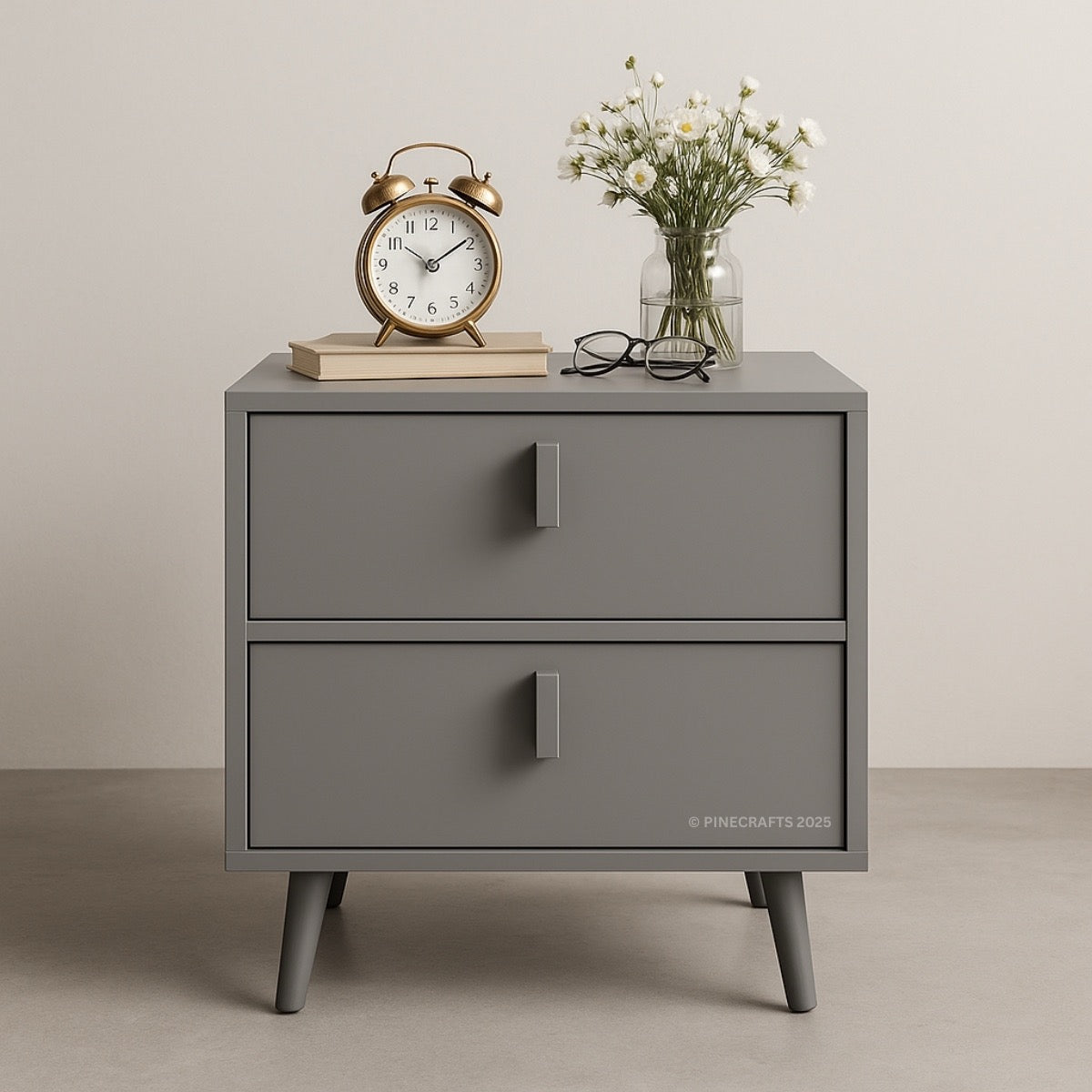 Gray nightstand with a clock, glasses, and flowers on top against a beige background