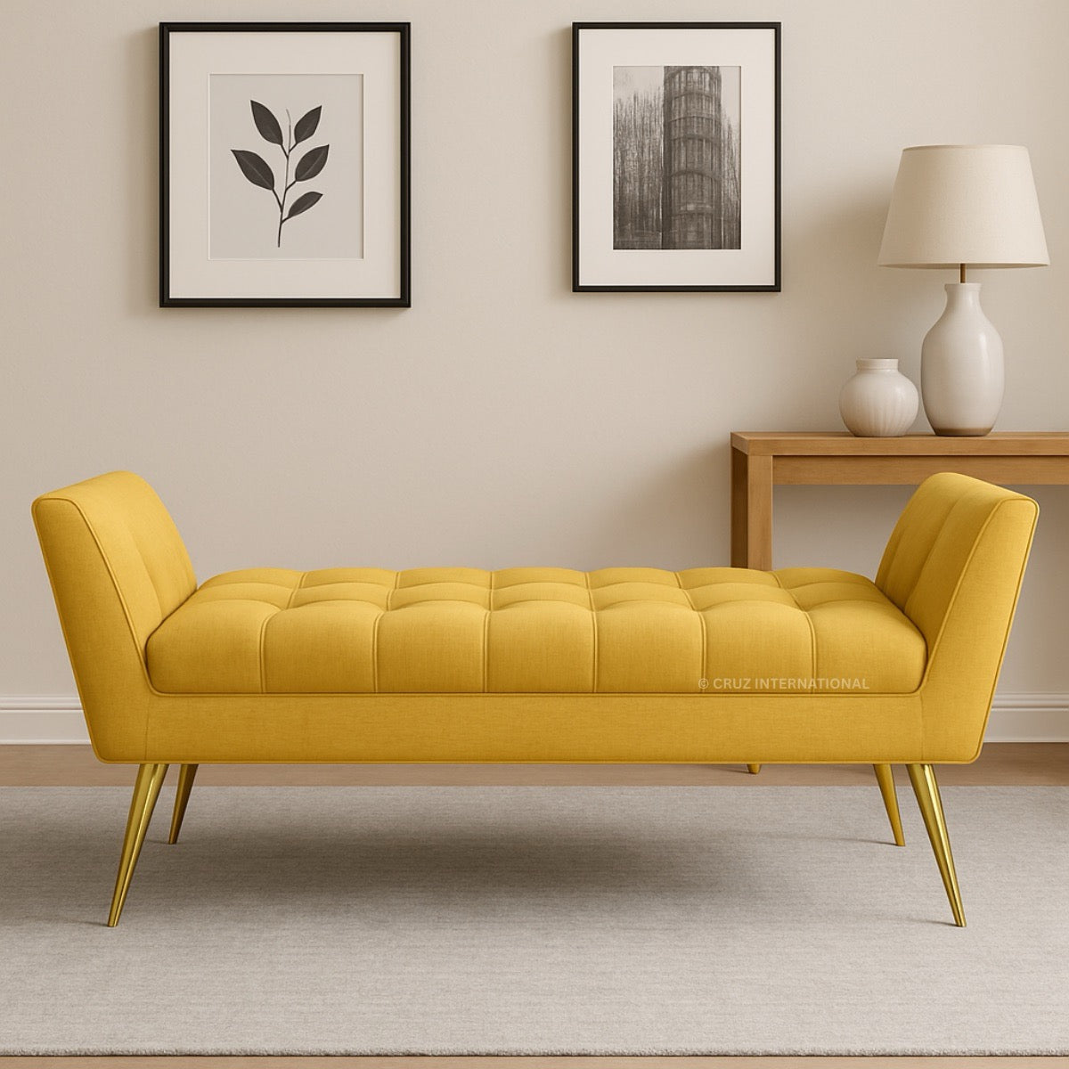 Yellow bench with gold legs in a room with framed pictures and a lamp.