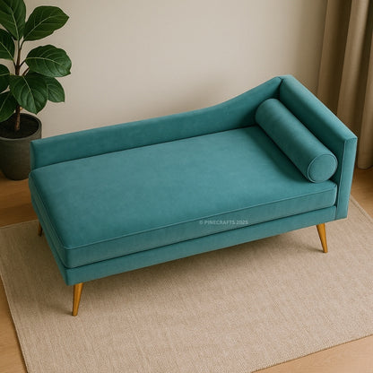 Teal sofa with gold legs on a beige rug, plant to the left.