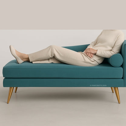 Person lying on a teal sofa with gold legs against a plain background