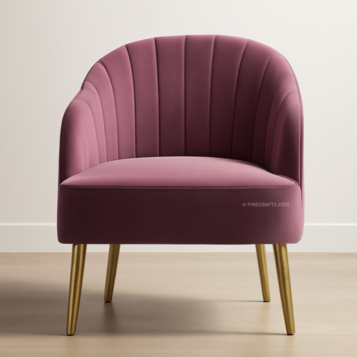 Pink velvet armchair with gold legs on a light wooden floor and white wall background