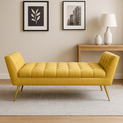Yellow tufted bench in a room with a lamp, table, and wall art.