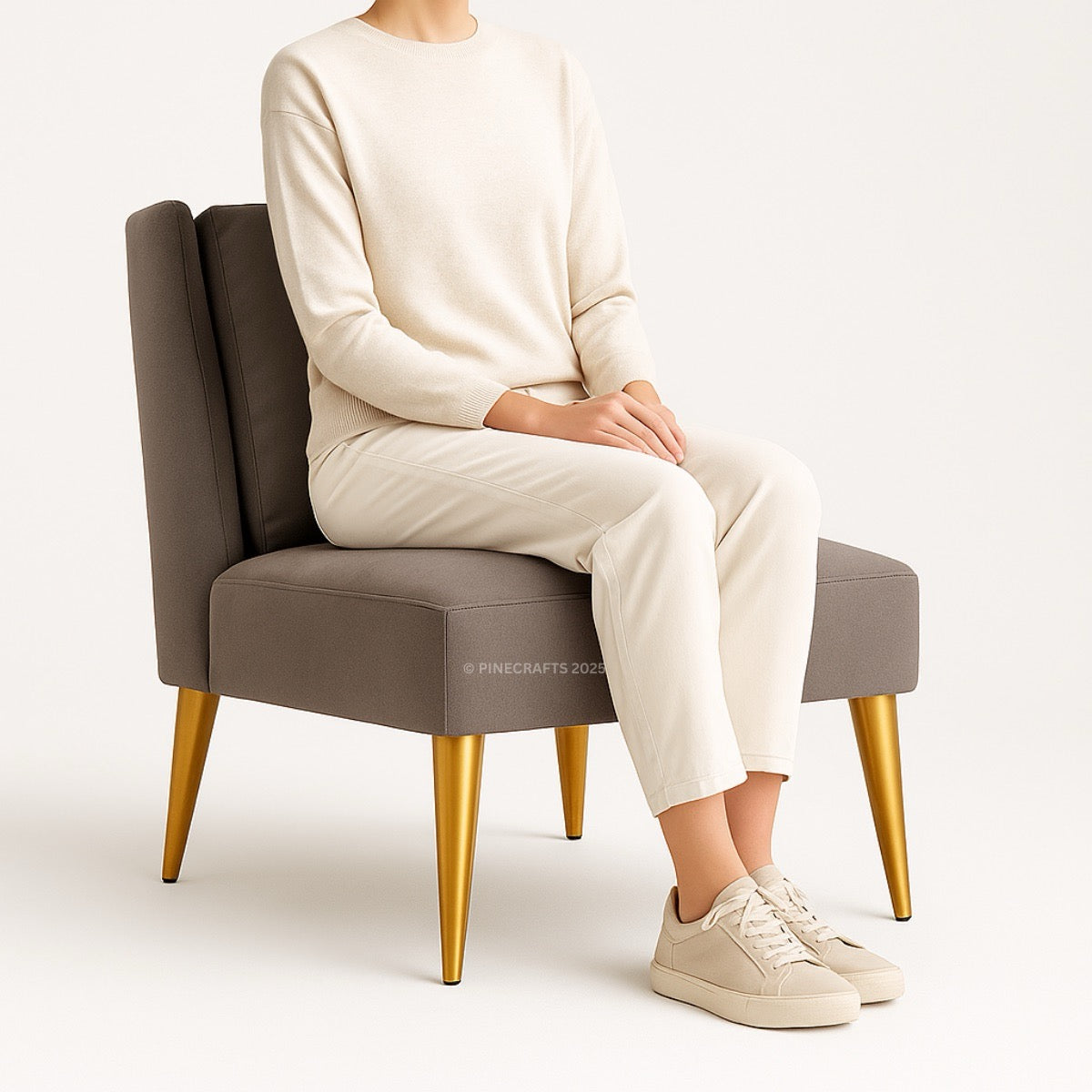 Person sitting on a gray chair with gold legs wearing a white outfit.