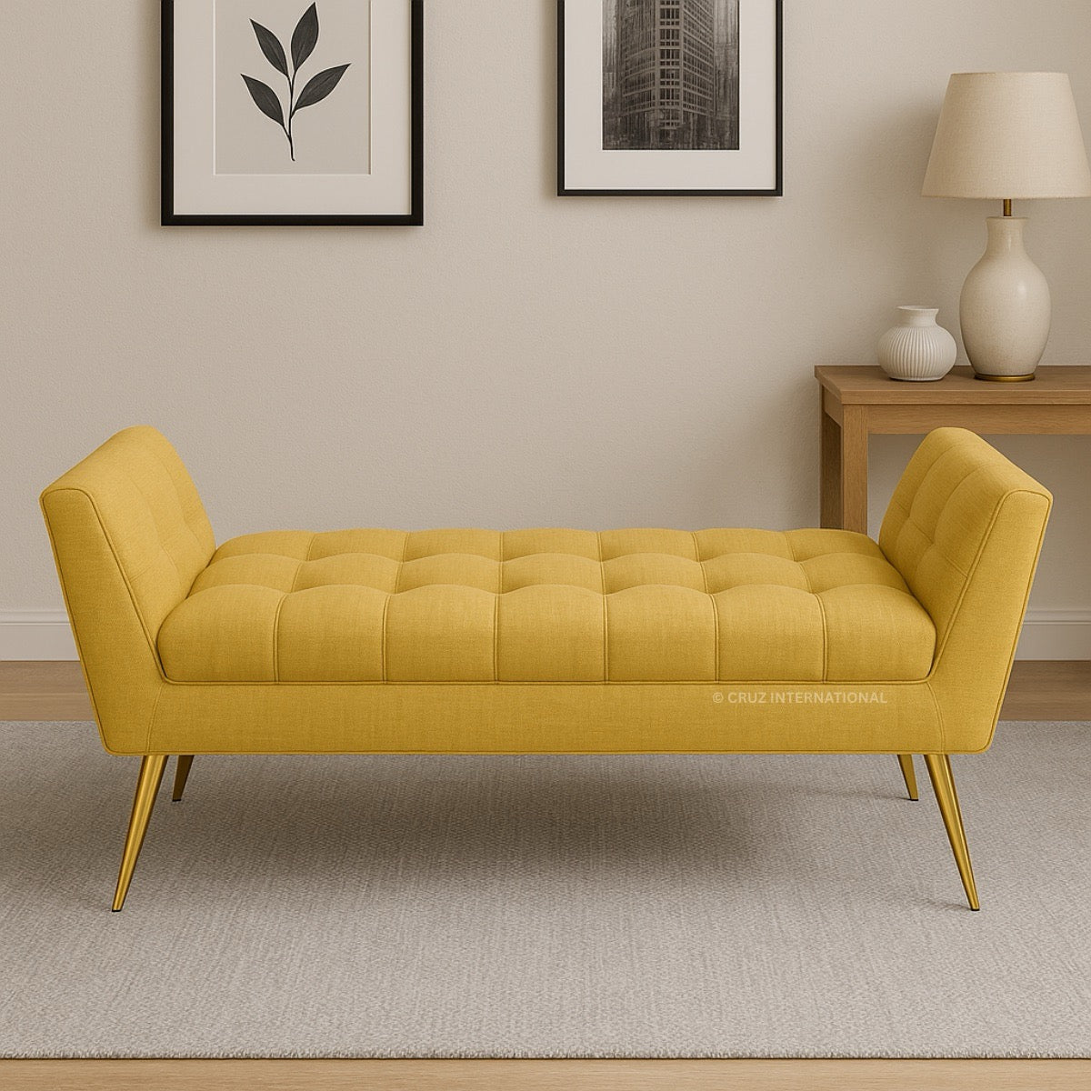 Yellow tufted bench in a room with a lamp and decor items on a table.