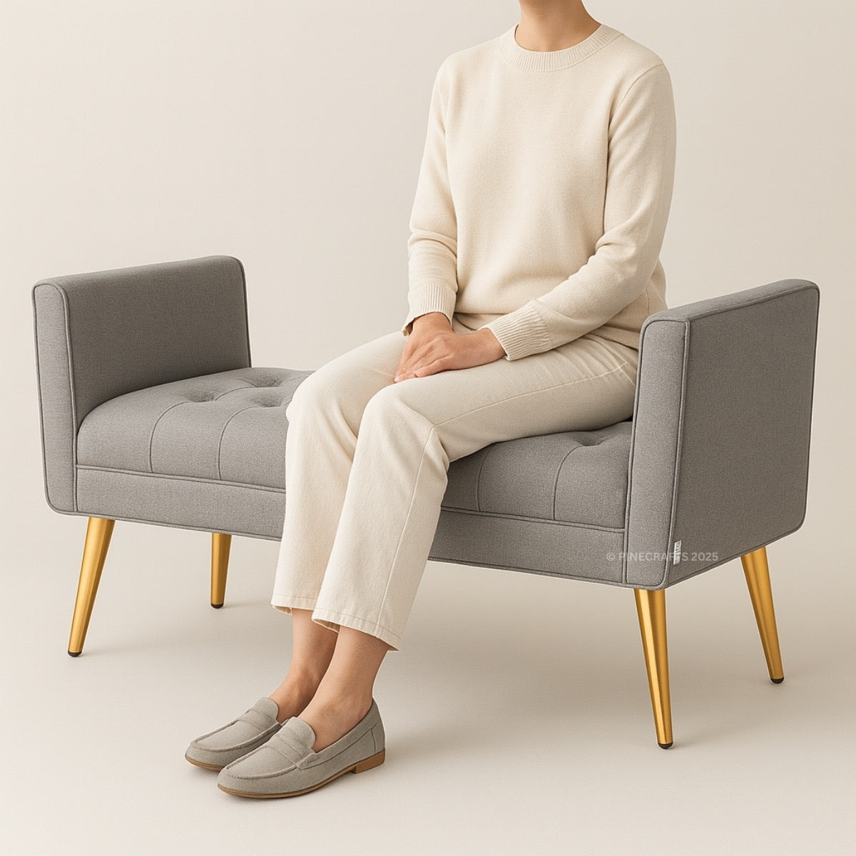 Person sitting on a gray chair wearing a cream sweater and pants with gray shoes.