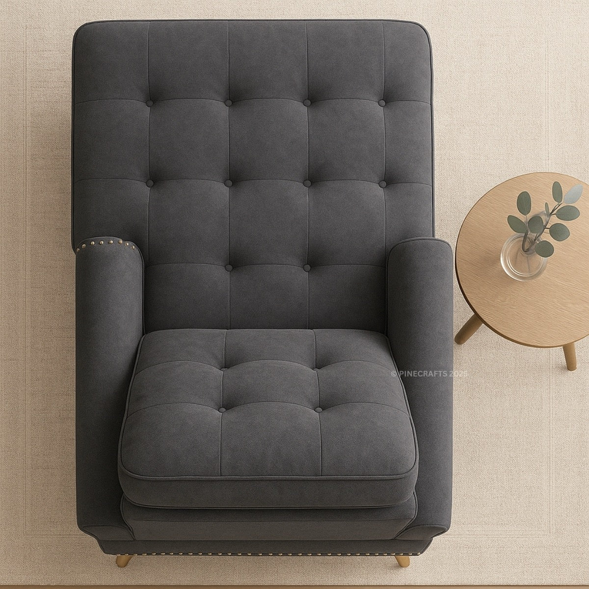 Gray tufted armchair in a room with a small round table and plant.