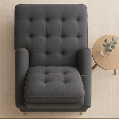 Gray tufted armchair in a room with a small round table and plant.