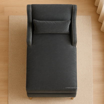 Dark gray upholstered chair with a pillow on a wooden floor.